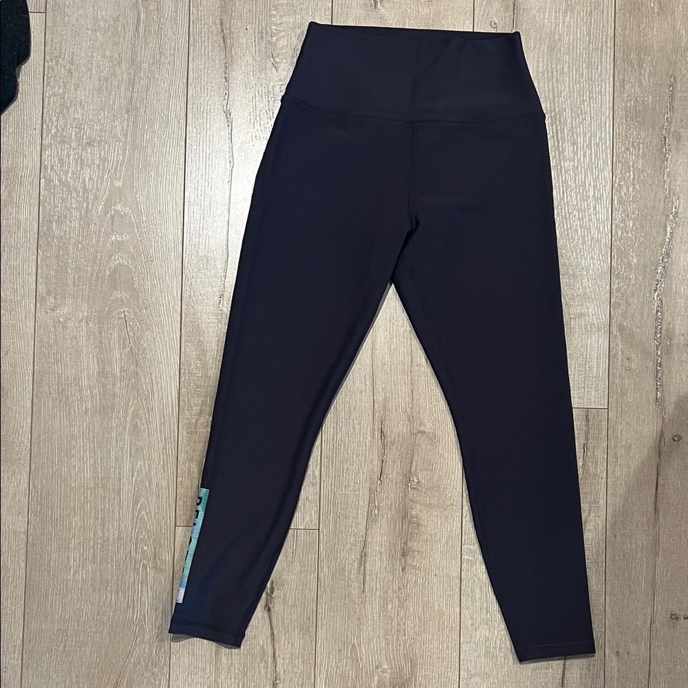 Peloton dark grey leggings with colorful logo.